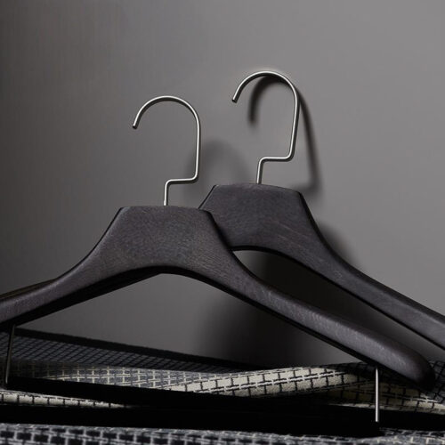 Black wooden hangers arranged on apparel rack